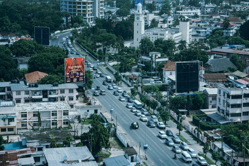 Drone shot capturing busy street and lush greenery with cityscape.