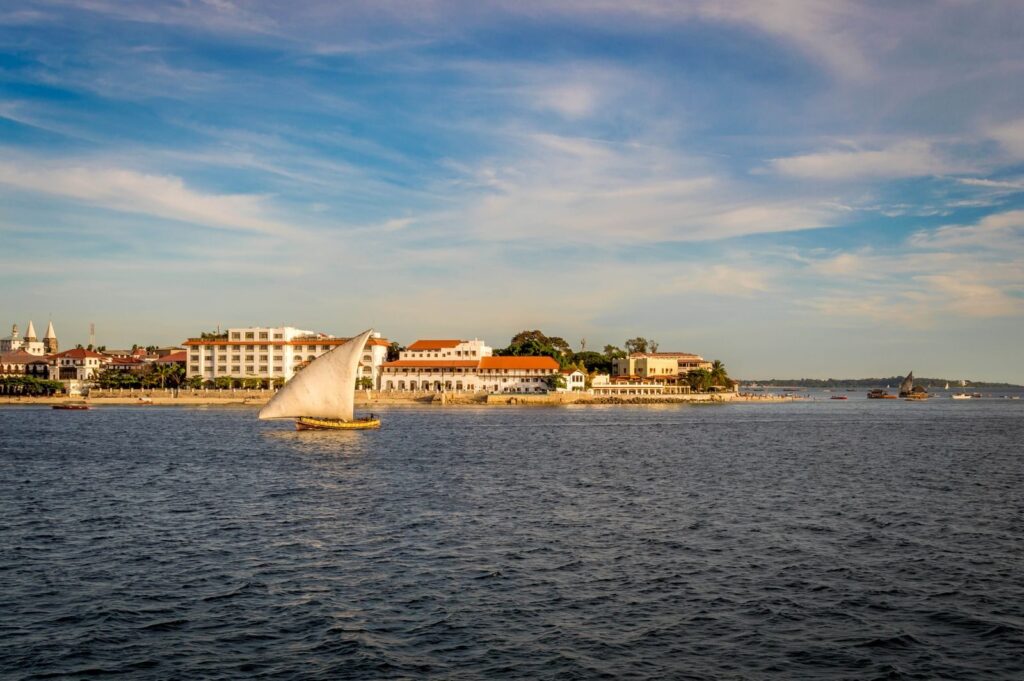 Charming sailboat on the vibrant waters of Zanzibar against a historic cityscape.